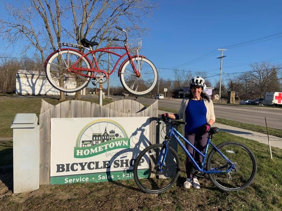 Hometown Bicycles Events Coordinator and Zumba instructor Leslie Barrett with her bicycle in front of the Hometown sign